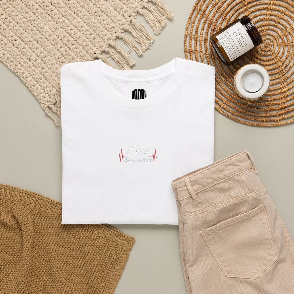 White t-shirt with 'Dieu' logo, beige pants, and decorative items on a neutral background