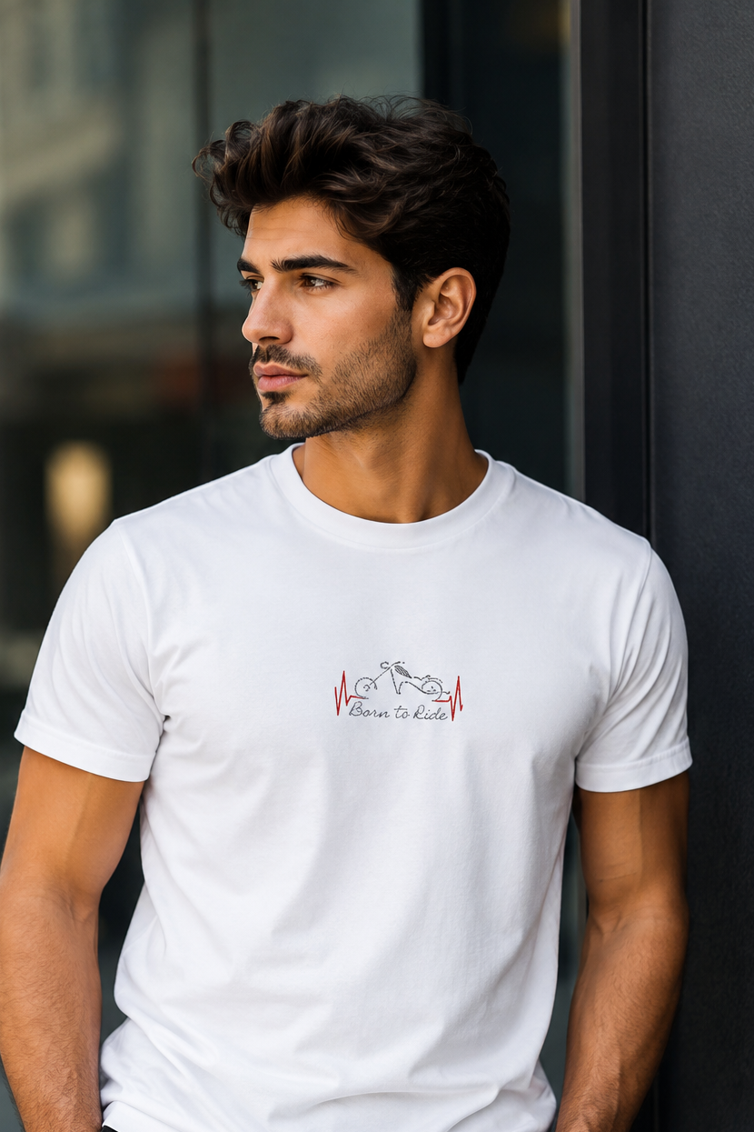 Man wearing a white t-shirt with a logo, standing against a dark wall.